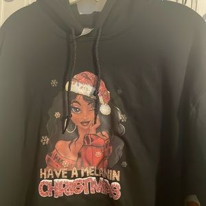 A black, woman’s hoodie “have a melanin Christmas” with a beautiful image.